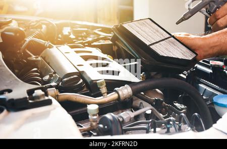 Car air filter in auto mechanic hand is blowing dust and cleaning with air blow gun Stock Photo