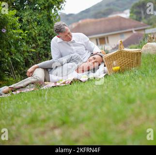 Deeper love comes with maturity. a loving mature couple having a picnic on the grass. Stock Photo