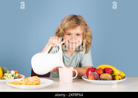 Healthy child pours milk from jug. Healthy breakfast for kids. Child drink dairy milk. Stock Photo