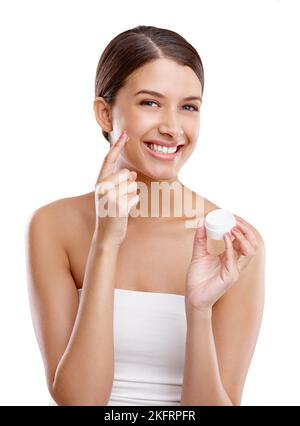 The steps to beautiful skin. Studio portrait of a beautiful young woman applying moisturizer to her skin. Stock Photo