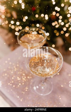 New Year's Eve 2022-2023 Celebration Background with Champagne. Champagne glasses on glitter background. Christmas decorations. Stock Photo