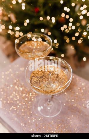 New Year's Eve 2022-2023 Celebration Background with Champagne. Champagne glasses on glitter background. Christmas decorations. Stock Photo