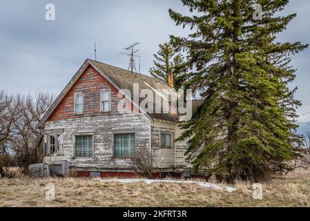 Moody skies over an old, abandoned pink home on the prairies in Saskatchewan Stock Photo