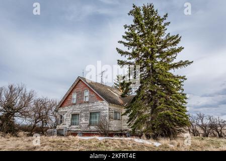Moody skies over an old, abandoned pink home on the prairies in Saskatchewan Stock Photo