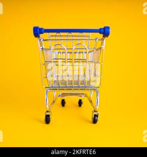 empty shopping cart over colour background, mini metal cart isolated on color background Stock Photo