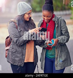 Read this...two girlfriends looking at a cellphone while on campus. Stock Photo
