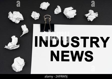 Industrial concept. On a black background, there are crumpled pieces of paper and paper with the inscription - Industry News Stock Photo