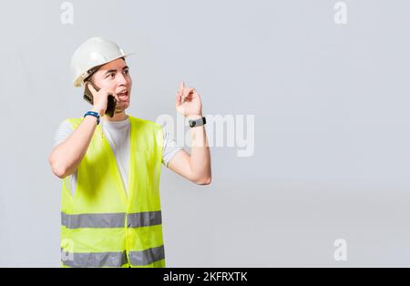 Builder engineer in vest talking on cell phone isolated. Civil engineer concept talking on cellphone isolated, Smiling engineer talking on the phone i Stock Photo