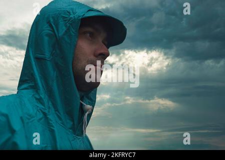Depressive concept with lonely man in raincoat standing on wet road under rain close up Stock Photo