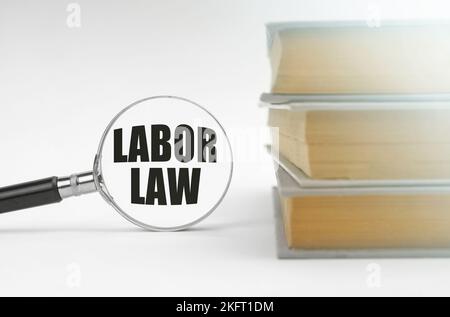 Education concept. On a white background, books and a magnifying glass, inside which it is written - Labor Law Stock Photo