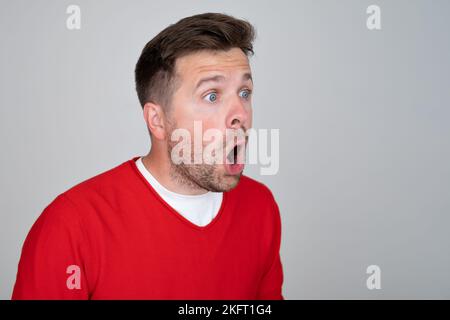Shocked unshaven man expressing surprise on camera isolated over gray background Stock Photo