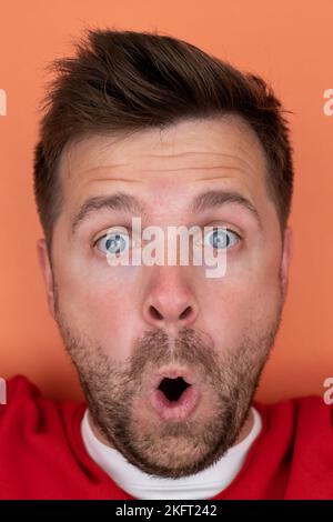 Shocked unshaven man expressing surprise on camera isolated over gray background Stock Photo