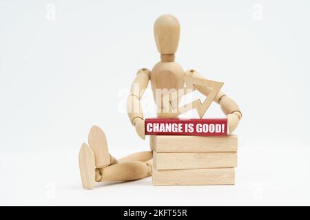 Business and Economics. On a white background, a wooden man sits near the wooden blocks, he holds in his hands a red block with the inscription - Chan Stock Photo