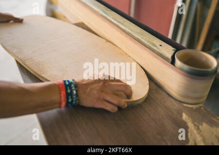 Anonymous male carpenter using belt sander machine on wooden board in workshop Stock Photo