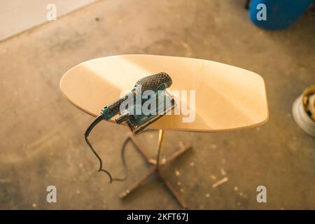 From above of electric sander placed on wooden ironing board in carpentry workshop Stock Photo