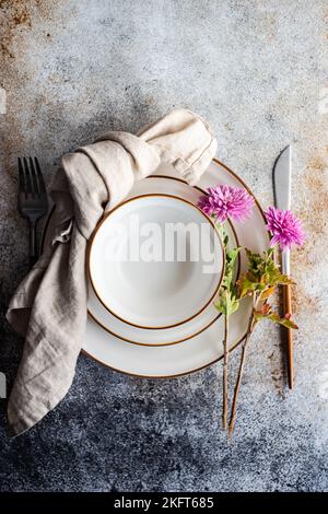 Place setting with purple Chrysanthemum flowers on concrete table with plates Stock Photo