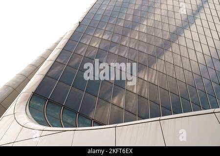 Low angle perspective of exterior of high rise building with paneled wall shining in sun Stock Photo