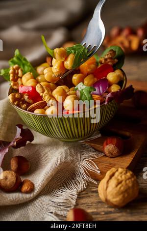 From above appetizing colorful cut vegetable mix with chickpeas and walnuts on wooden background Stock Photo