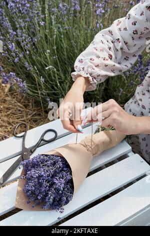 Vertical photo. Packing a bouquet of lavender in craft paper on a lavender field. Stock Photo