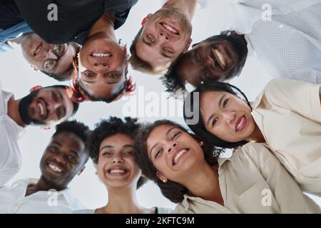 group of diverse young people standing in a circle and looking down Stock Photo