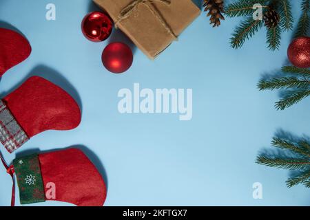 Beautiful Christmas composition on blue background. Christmas present boxes,socks, fir spruce branches,, conifer cones, caramel stick, gift. New Year. Stock Photo