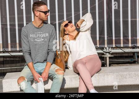 Couple sitting on a bench, in the sun, the woman basking. Stock Photo