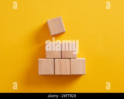 Pyramid of blank wooden cubes on yellow background. Stock Photo