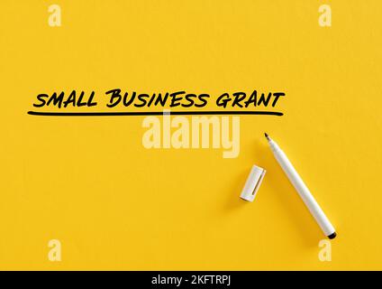 Small business grant on yellow background with felt tip pen. Stock Photo