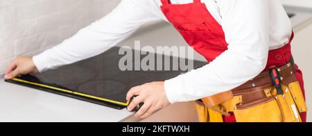 craftsman installs hob in kitchen. Household Appliance Installation Services Concept Stock Photo