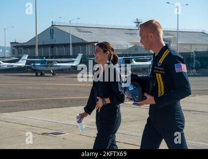 OAKLAND, California (Oct. 07, 2022) Aviation Electrician's Mate 2nd Class Sean Donoghue, assigned to the Navy Flight Demonstration Squadron, the Blue Angels, escorts Monica Barbaro, Top Gun: Maverick actress, across the flightline. The Blue Angels perform flight demonstrations at 32 locations across the country to showcase the teamwork and professionalism of the U.S. Navy and Marine Corps to the American public. Stock Photo