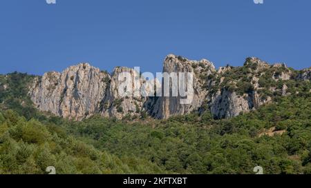 Colorful summer landscape panorama of rocky mountain ridge emerging from forest in the Aude Pyrenees near Salvezines, France Stock Photo