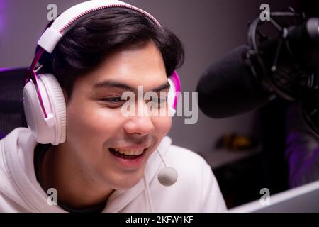 Young asian man for a podcast wearing headphones and speaking with mic in studio, host male or DJ wearing headset talking with microphone for entertai Stock Photo