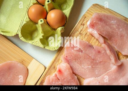 Eggs in a carton box and meat for chops on the table, top view Stock Photo