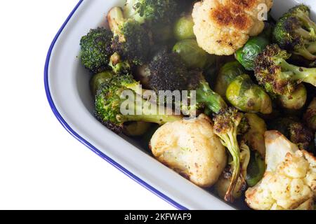 Brussels sprouts, cauliflower and broccoli, oven roasted in olive oil,  in an enamel dish bowl. Isolated on a white background Stock Photo