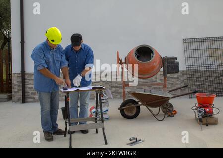 Image of an engineer and construction worker on a construction site as they consult the plan of the project to be implemented. Construction work Stock Photo