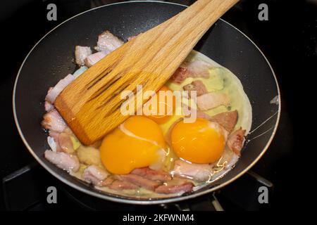 Scrambled eggs with bacon in a pan. Stock Photo