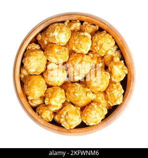 Caramel popcorn, caramel corn, toffee popcorn, in wooden bowl. Confection made of popped popcorn, with sugar or molasses based caramel candy shell. Stock Photo