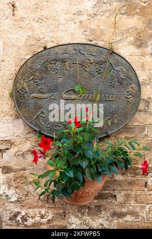 Copper sign and a terracotta pot with a plant a wall of the restaurant Ristorante La Cantina di Spello in the Italian village of Spello in the Perugia. Stock Photo