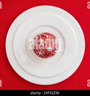 Christmas table setting. Xmas bauble on plates on red background, top view. Holiday celebration dinner Stock Photo