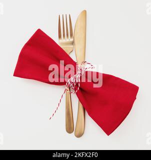 Holiday table setting. Golden Cutlery and red cloth napkin isolated on white, top view. Christmas New Year , celebration dinner Stock Photo