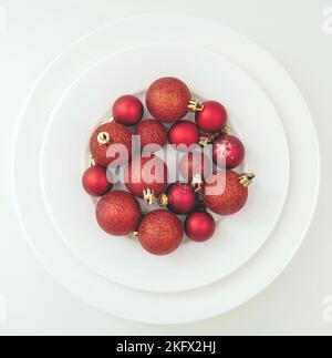 Holiday celebration dinner, Christmas table setting top view. Red Xmas baubles on plates isolated on white background, top view. Stock Photo