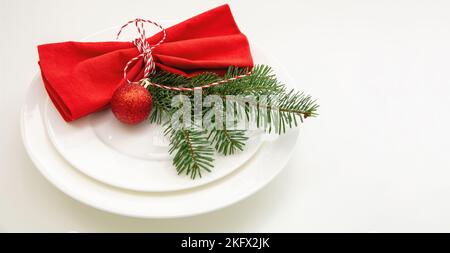 Christmas table setting, celebration dinner. Red cloth napkin and Xmas decoration on plates set, white background Stock Photo