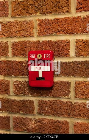 Manual fire alarm activation pull station on masonry wall Stock Photo