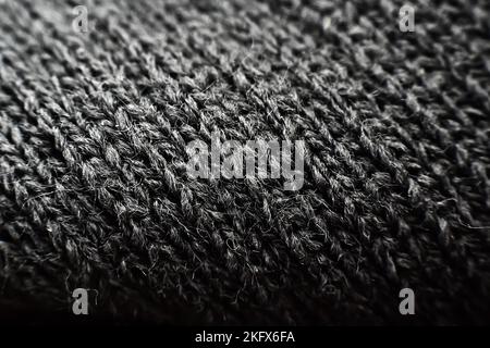 Texture of knitted fabric in dark color. Knitted material background Stock Photo