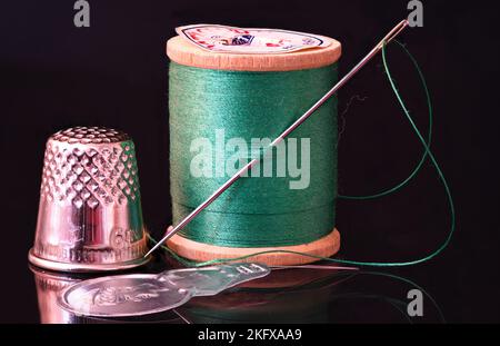 hand threading a needle with black thread Stock Photo - Alamy