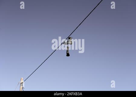 a pair of military boots with the laces attached to an electrical cable that crossed the blue sky Stock Photo