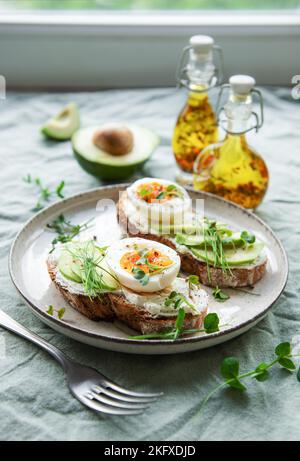 Bread toast, boiled eggs, avocado slice, microgreens on a plate, breakfast time Stock Photo