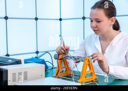 girl student studying the work of an electronic device in the electronics class Stock Photo