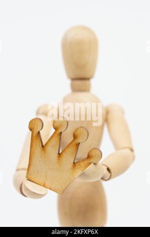 Business and leader concept. The wooden man holds a crown in his hands. Isolated on white background. Stock Photo