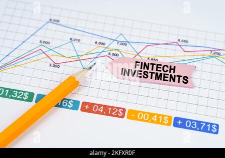 Business concept. On business charts there is a pencil and an arrow sticker with the inscription - FinTech investments Stock Photo
